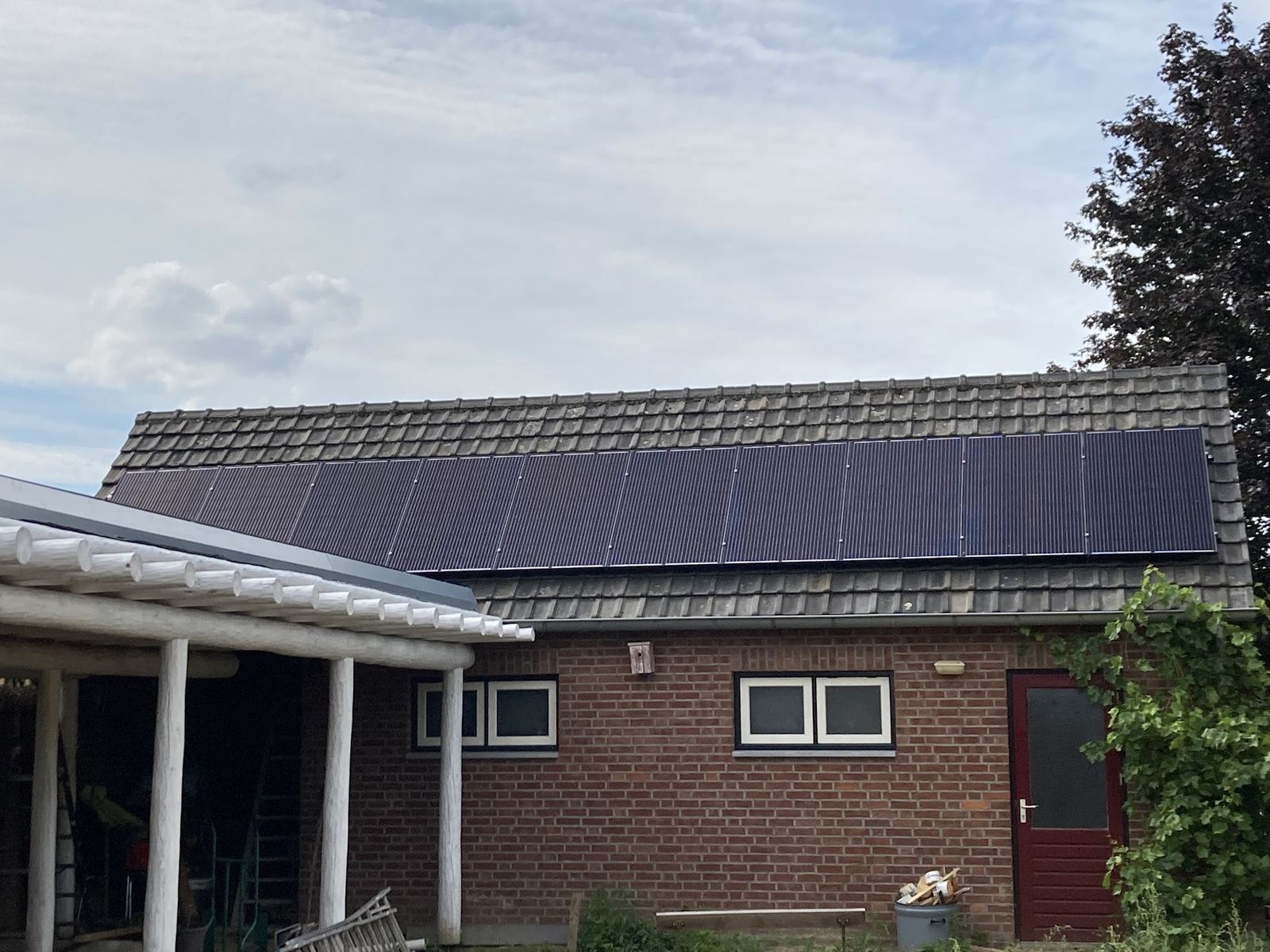 Volle rij zonnepanelen op een lang bakstenen bijgebouw