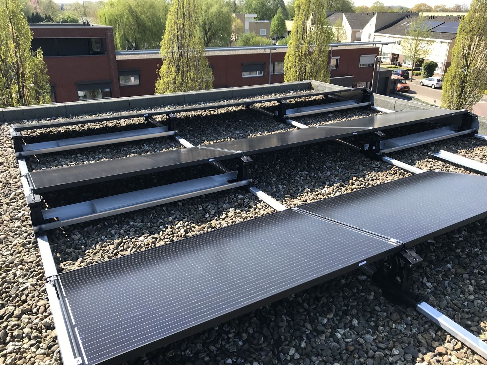 Oost-west opstelling van zonnepanelen met ballastbakken op een grinddak