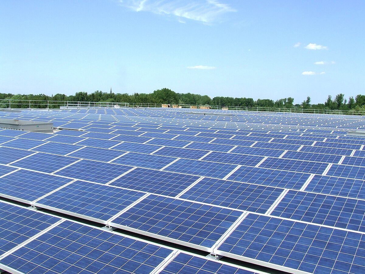 Groot bedrijfsdak vol zonnepanelen onder een blauwe lucht