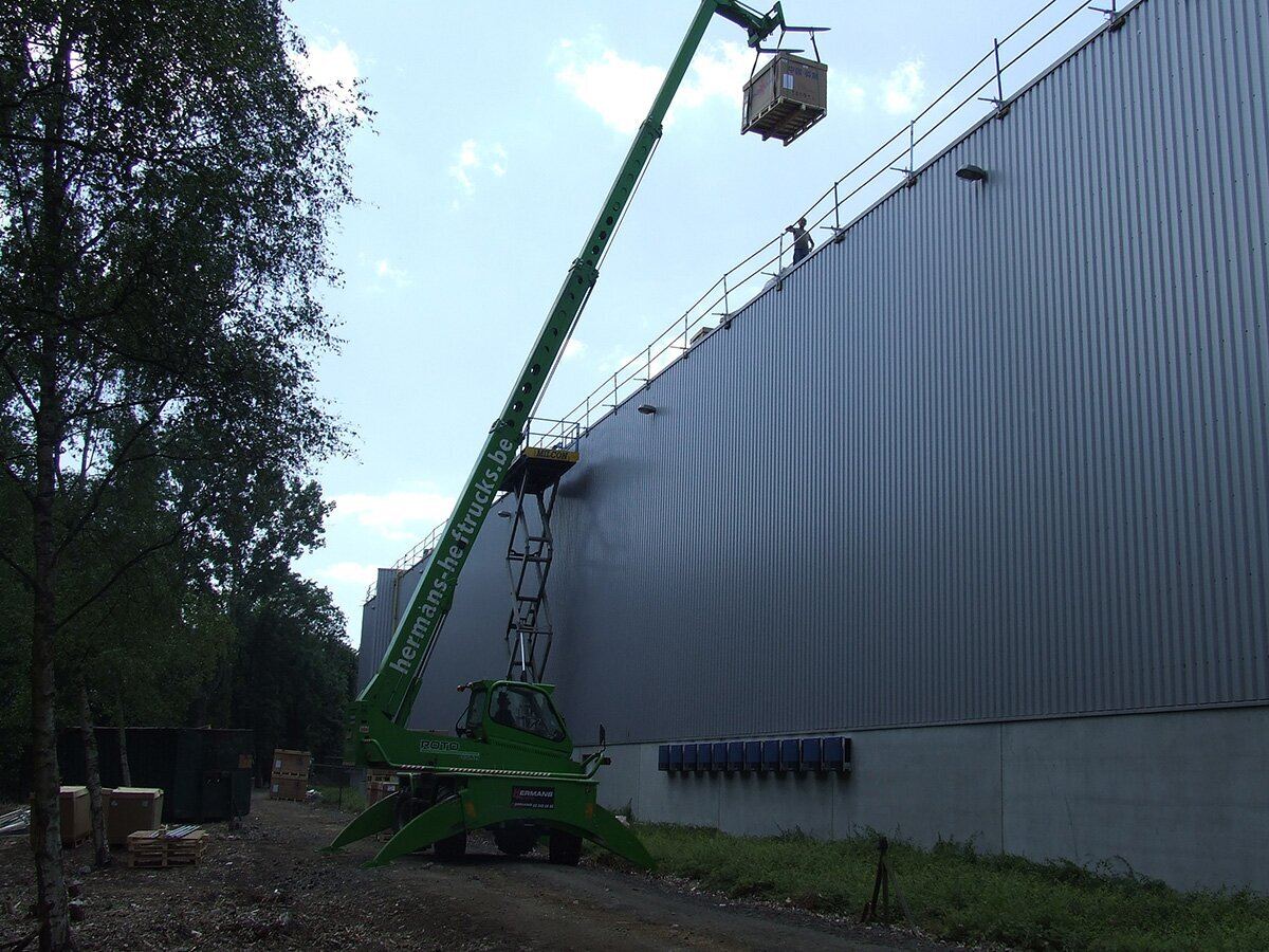 Hoogwerker hijst materiaal op het dak van een grote bedrijfshal