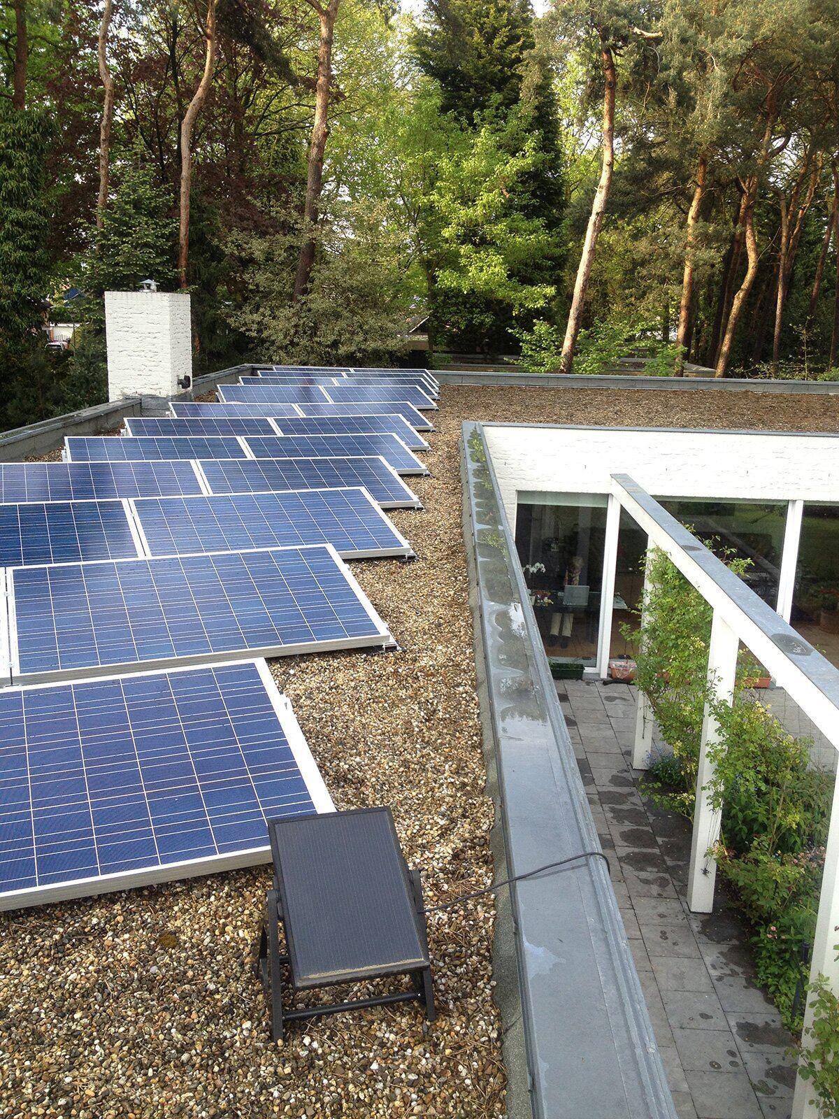 Zonnepanelen op het platte dak van een moderne villa tussen de bomen